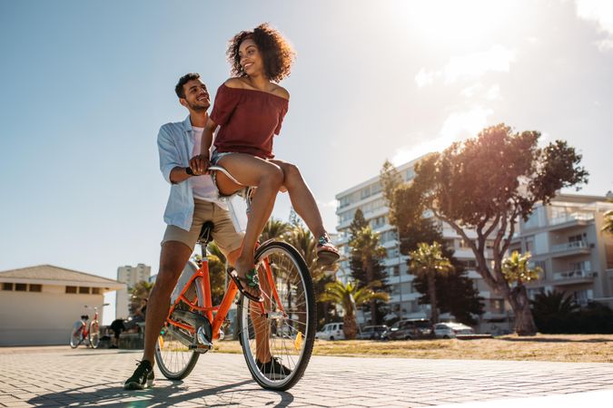 Happy man and woman having fun riding a bicycle on a sunny day