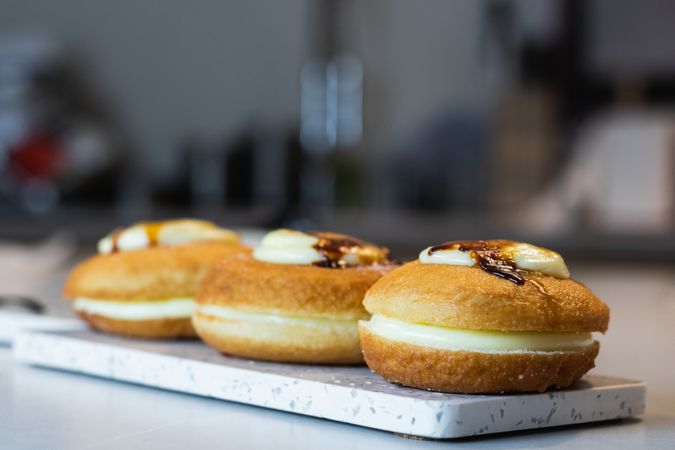 Crop cook with appetizing Berliners on tray in bakery