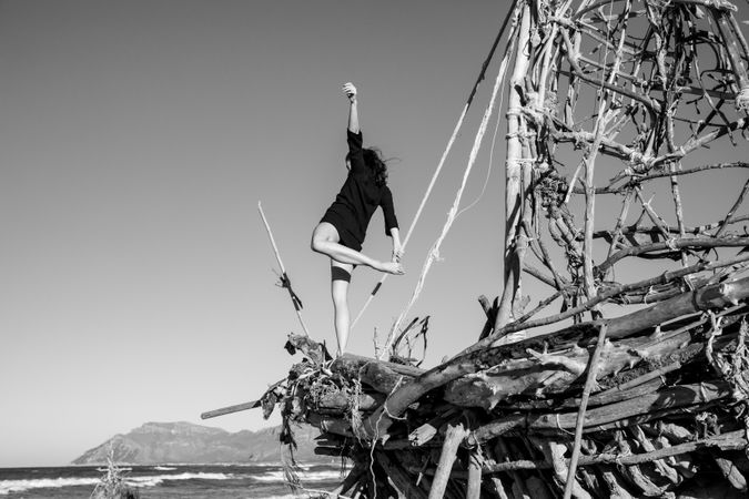 Young woman with upped leg on decorative wooden ship near water on shore