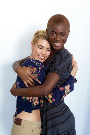 Affectionate female couple embracing happily in studio