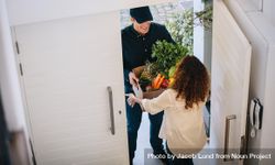 Delivery employee delivering a box of fruits and vegetables to a woman 0LVpX4