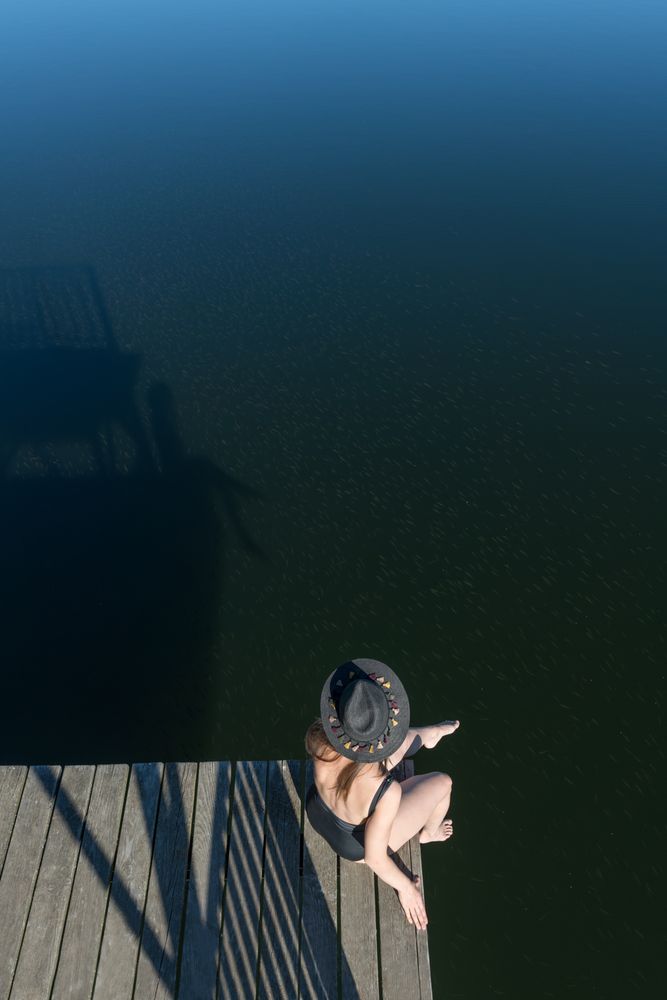 Young female sitting on pier on nature