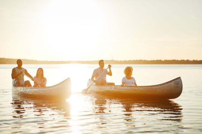 Multi-ethnic group of people canoeing at sunset