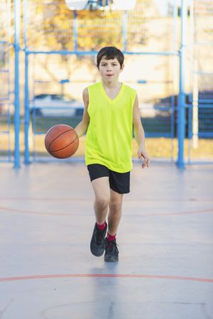 Teenager playing basketball on an outdoors court