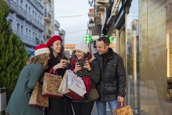 Happy friends standing with gifts and shopping bags on street in daylight