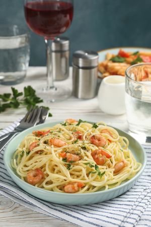 Composition with plate of tasty pasta with shrimps on wooden background