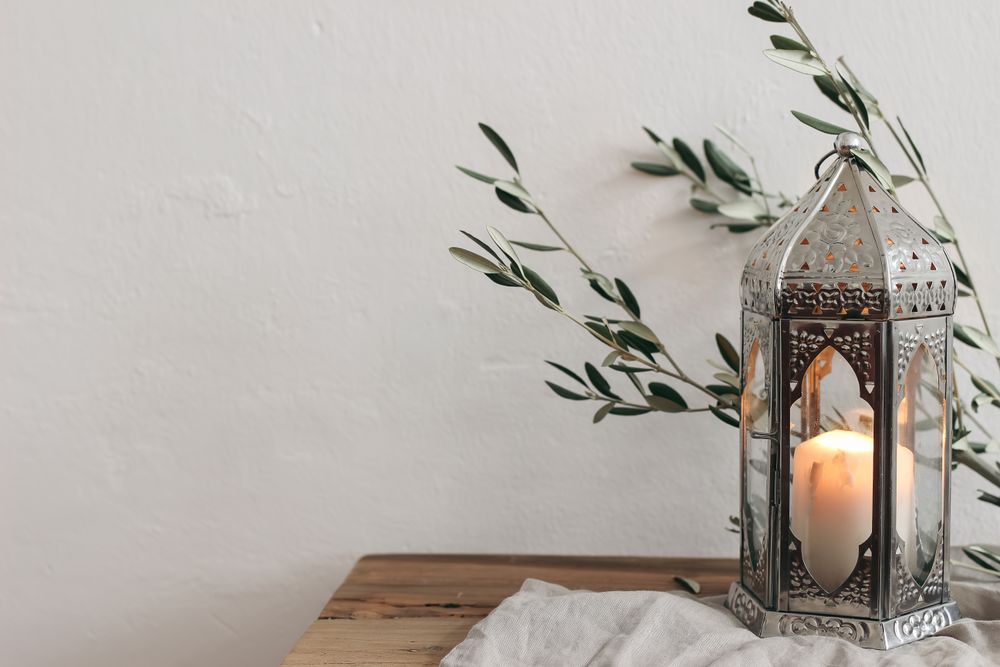 Ornamental silver Moroccan lantern with olive tree branches on wooden table