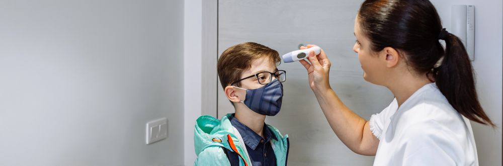 Mother checking her son's temperature before going to school