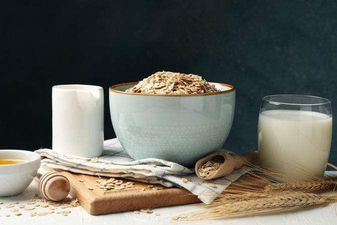 Composition with oatmeal flakes and milk on table. Cooking breakfast