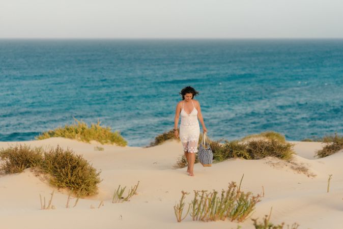 Active woman in white shorts walking sandy beach