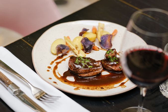 Plate of beef steak with vegetables served with red wine