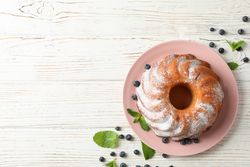 Cake with powder sugar and blueberry on wooden background, top view