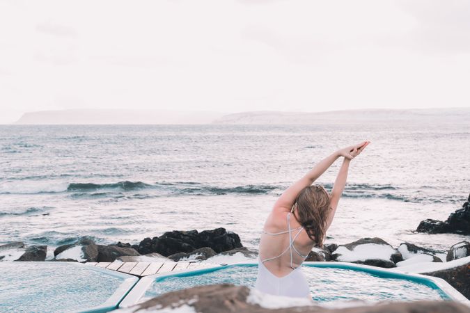 Woman sitting in pool near stones