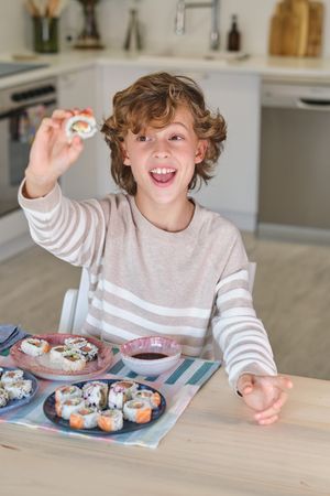 Cheerful boy eating rolls at home