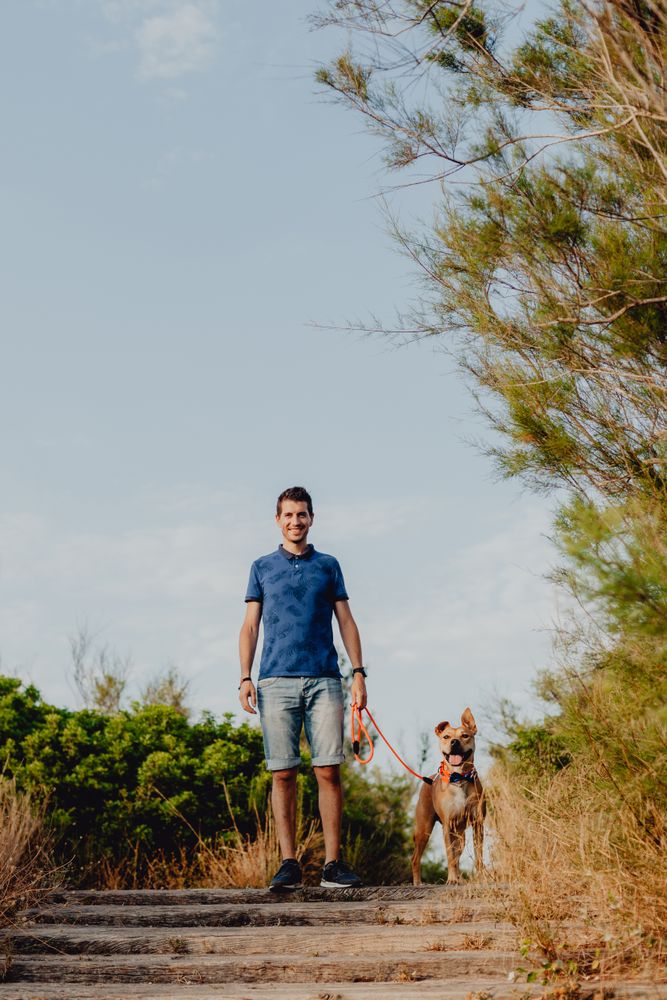 Happy adult man walking with dog along rural pathway