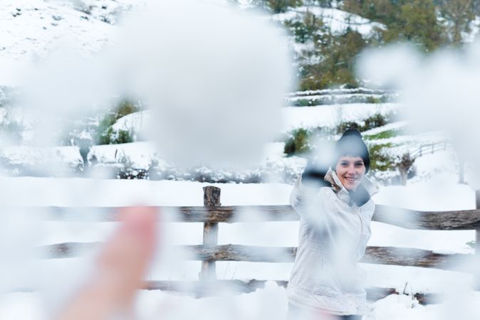 Smiling woman playing with snow in countryside