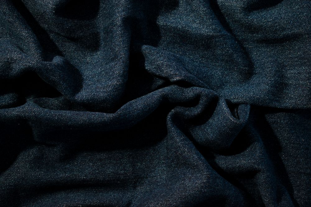 Close up detail crumpled wavy Navy blue jeans fabric background texture.