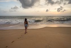 Woman in beachwear walking on sand barefoot