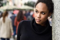 Portrait of serious woman in sweater outside with people in the background, copy space