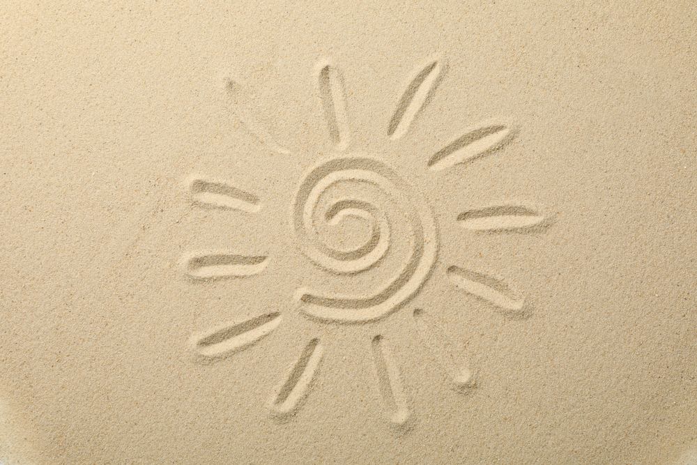 Suns drawing on dry sea sand, top view