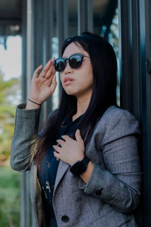 Sophisticated woman with sunglasses striking a stylish pose outdoors
