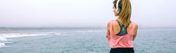 Sportswoman with headphones watching the sea