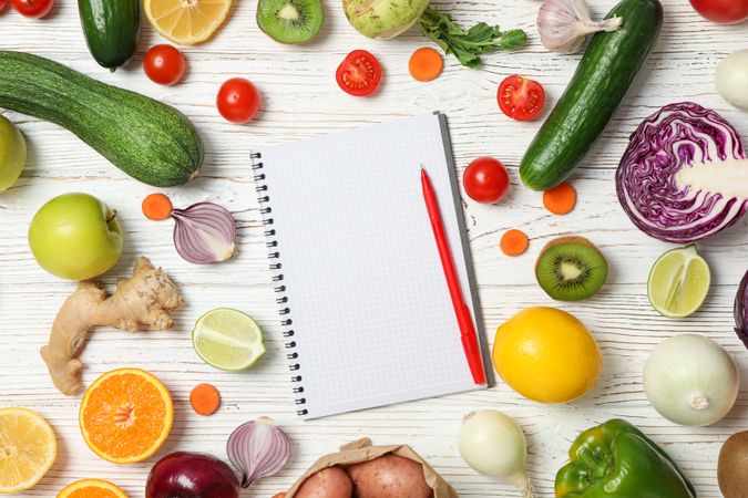 Vegetables, fruits and copybook with pen on wood background, top view