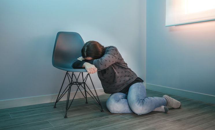 Depressed woman crying leaning on a chair