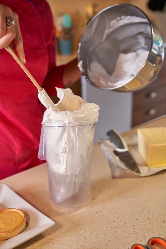Faceless woman filling pastry bag with whipped cream