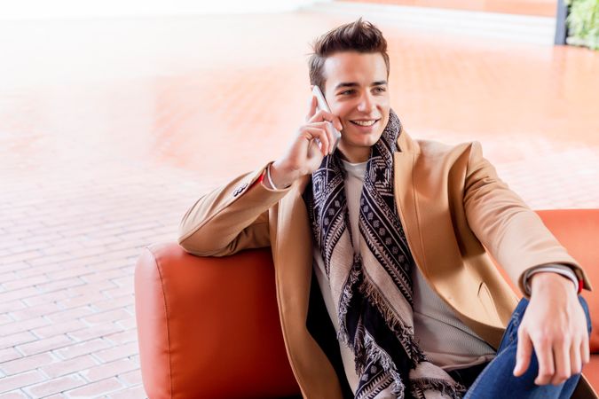 Happy man sitting on bench outside talking on cellphone