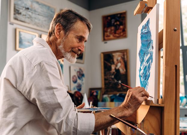 Older male painter in studio surrounding by art