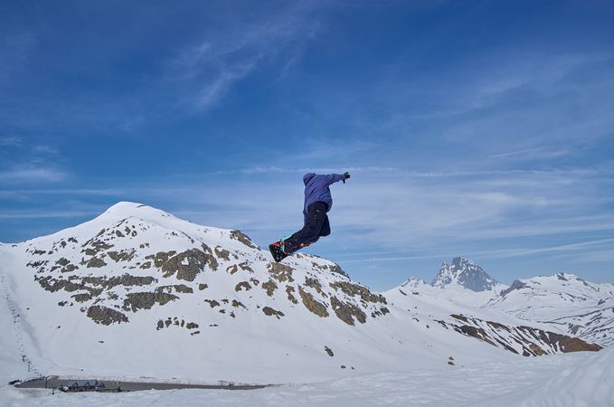 Unrecognizable snowboarder jumping on slope