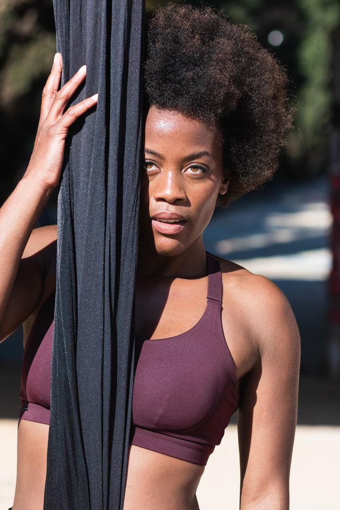 Fit Black woman with hammock for yoga in city