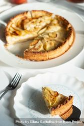 Apple tart with slice removed on ceramic plate with pie knife 5Q7N9b