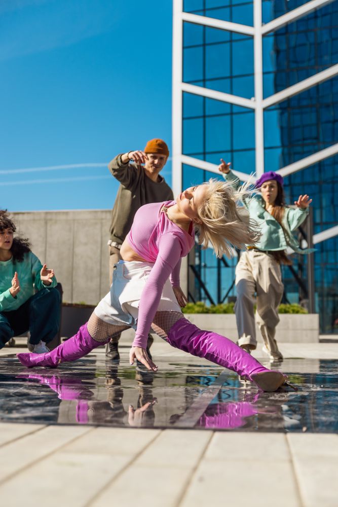 Vertical Screen: Fashionable Young Woman Wearing Pink Outfit Voguing On The City Street In Circle Of Stylish Friends.
