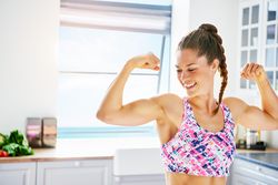 Woman smiling and looking at her arms as she flexes them