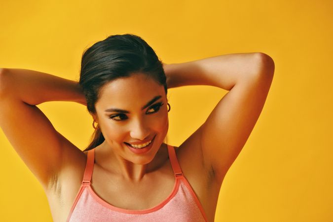 Headshot of Hispanic woman pulling her hair back into pony tail