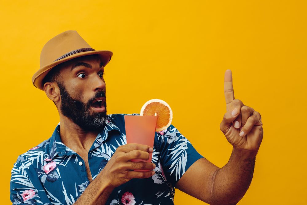 Amazed male giving pointing up while wearing colorful shirt with yellow background