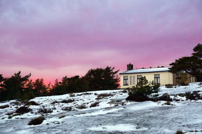Rural house at snowfield during majestic sunset