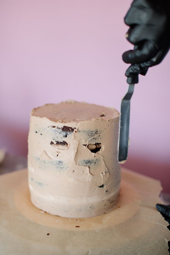Person putting icing on round cake
