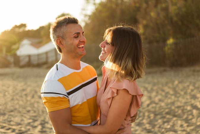 Laughing couple hugging on sandy beach