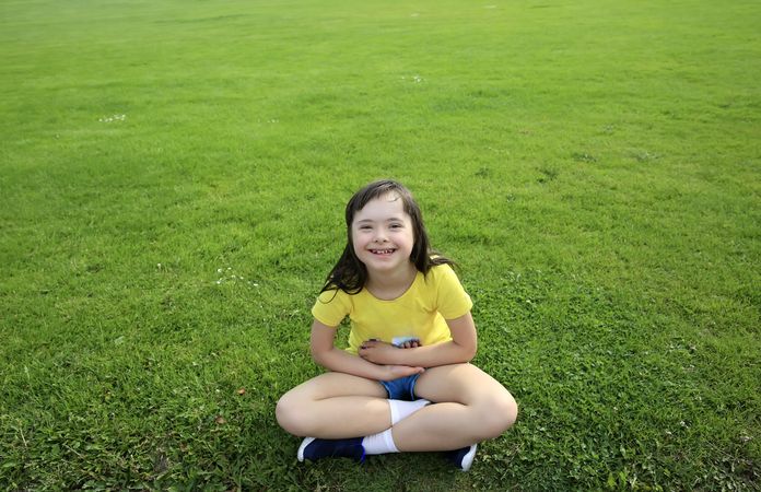 Happy child sitting on grass and looking at camera
