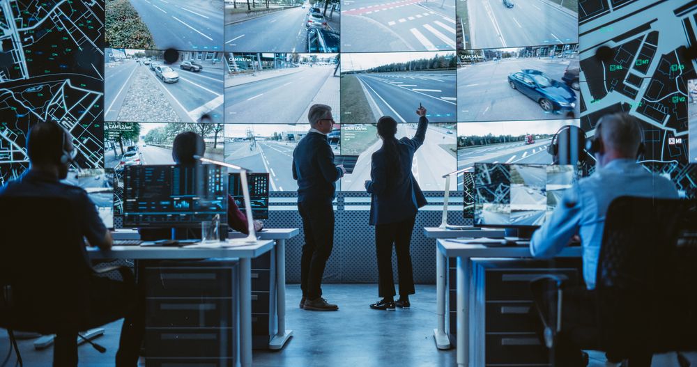 Traffic Commission Project Manager and Road Planning Department Computer Science Engineer Talking while Using Big Digital Display in a Monitoring Room.