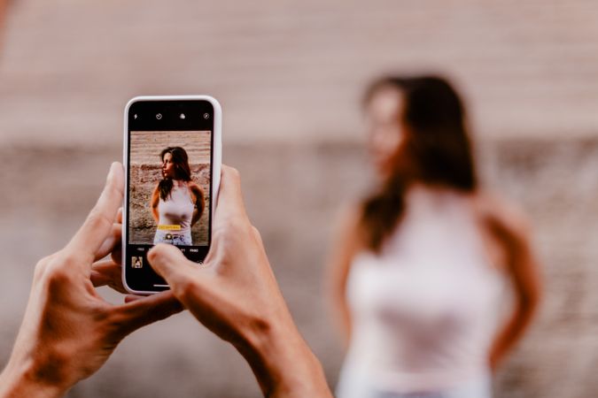 Faceless male taking photo of brunette woman