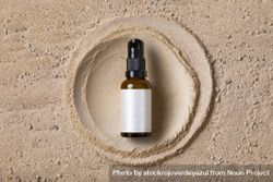 Mockup of an amber glass bottle of a cosmetic product on a sand texture and a circle 41lloj