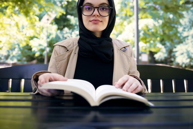 Middle Eastern woman sitting at park table with book