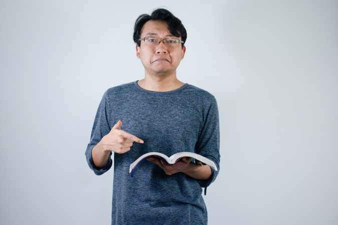Asian young male reading book and pointing down