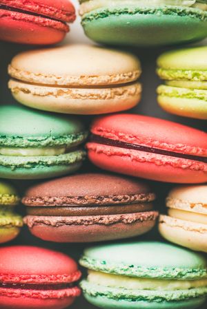 Bright multi-colored macaron pastries tightly stacked, side view, vertical composition, close up