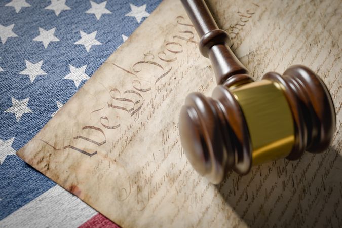 United States Constitution, Gavel and American Flag Resting on Table.