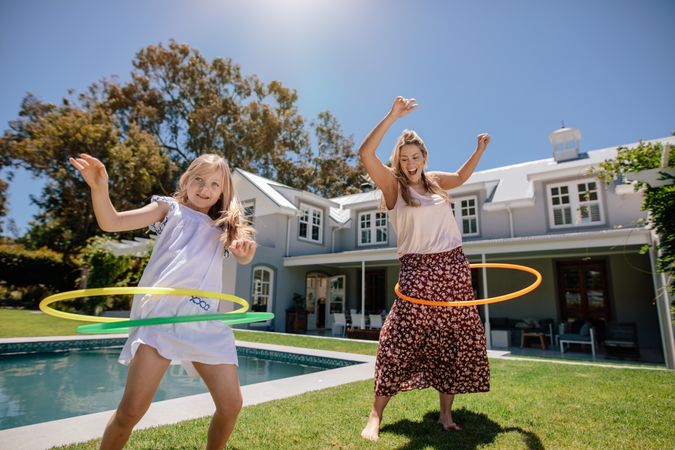 Mother and daughter having fun hula hooping outdoors